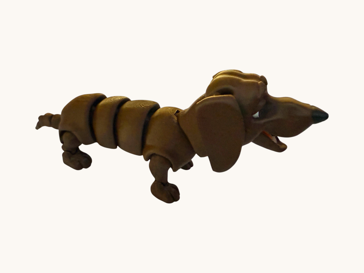 Flutterby Creations brown flexible dachshund 3D printed toy with segmented body and articulated limbs.