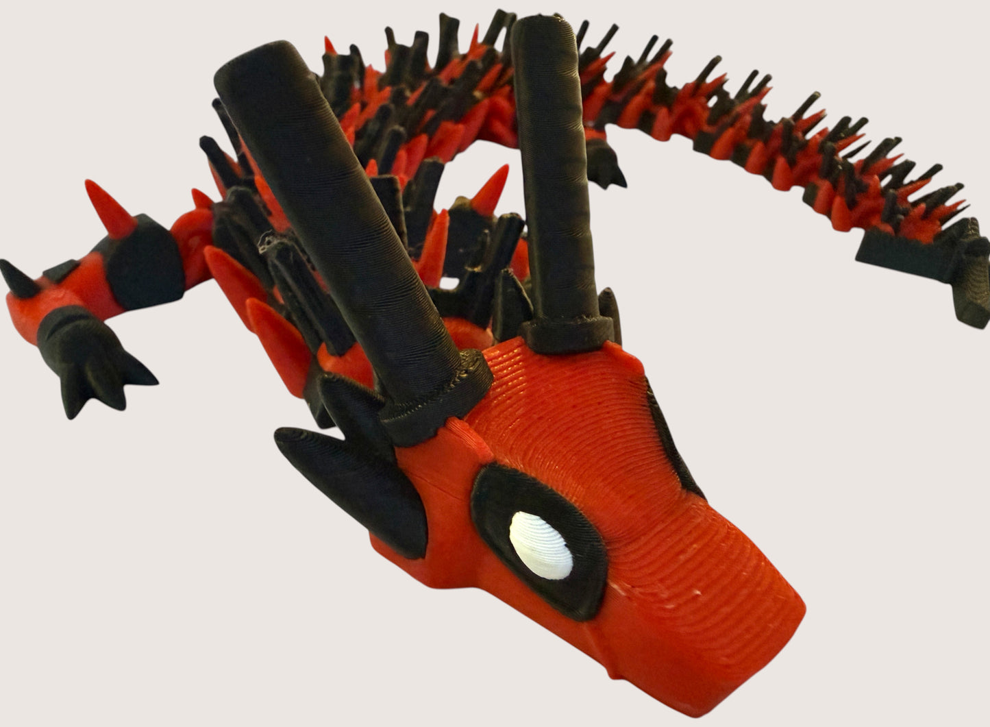 Flutterby Creations red and black 3D printed dragon toy with flexible segments and horns.