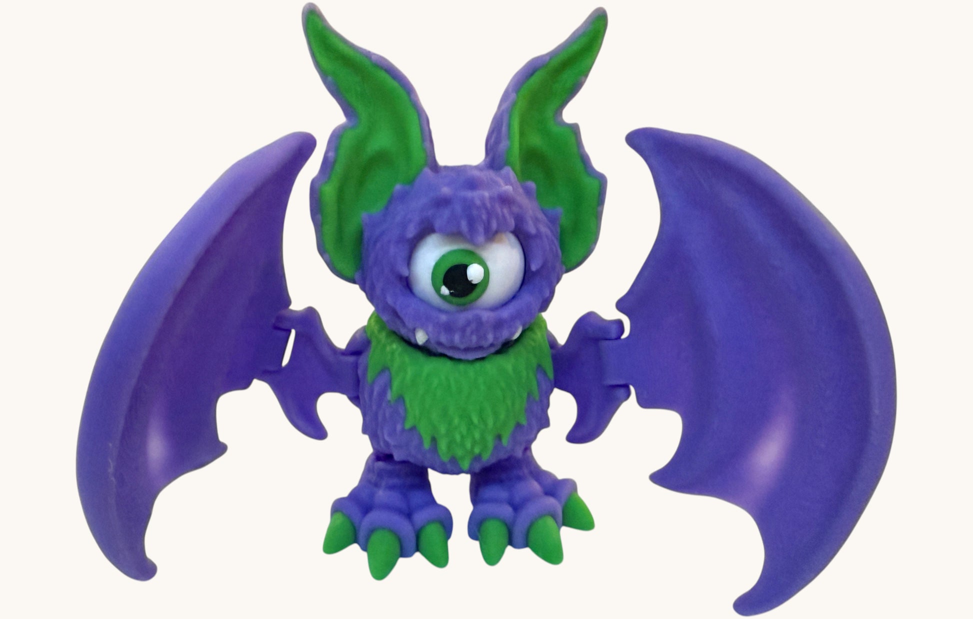 Flutterby Creations All Seeing Bat toy, purple with green wings and accents, one eye, fuzzy texture.