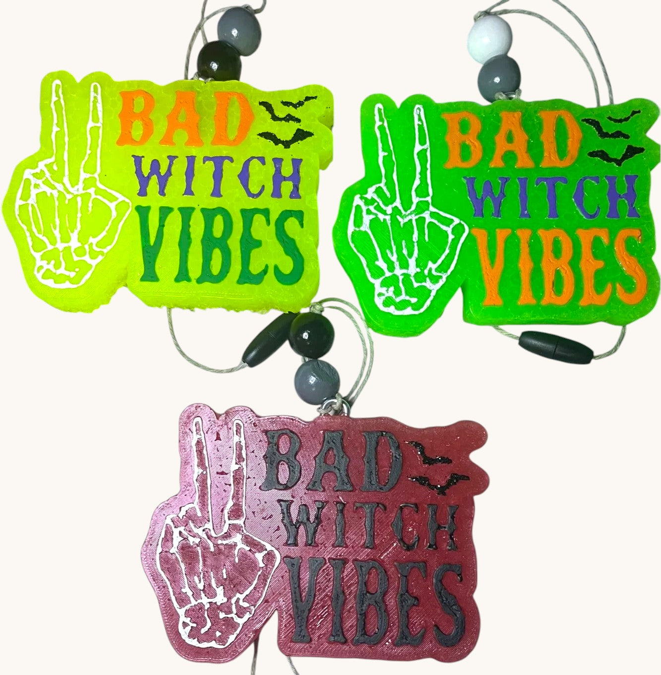 Flutterby Creations Bad Witch car freshie in neon green, lime green, and burgundy with skeleton hand peace sign and bats.