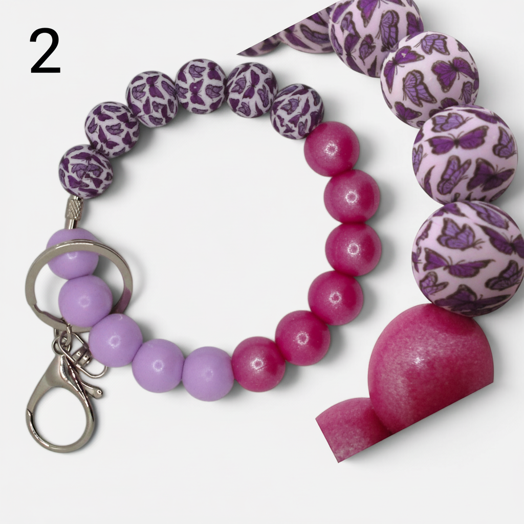 Flutterby Creations beadable wristlet featuring purple butterfly print beads and pink round silicone beads.