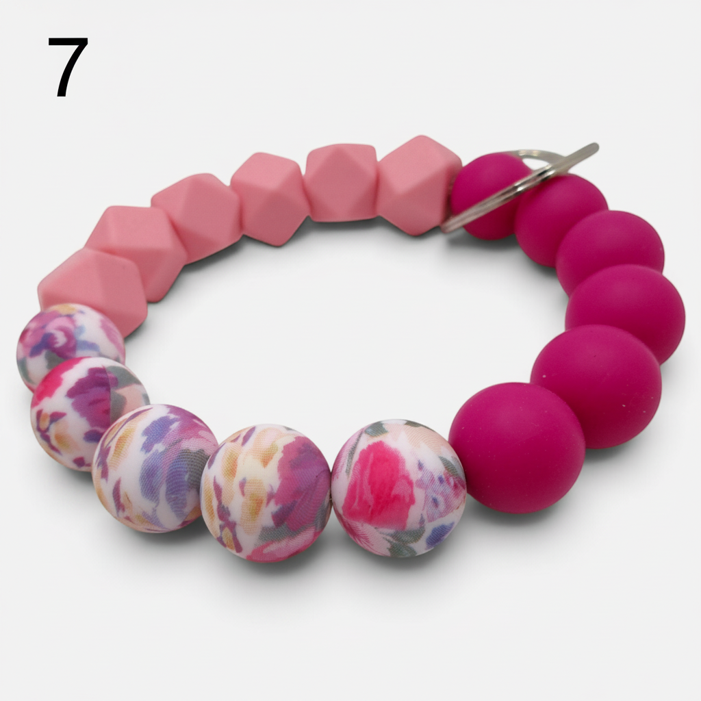 Flutterby Creations beadable wristlet featuring pink, fuchsia, and floral patterned silicone beads with a metal ring.