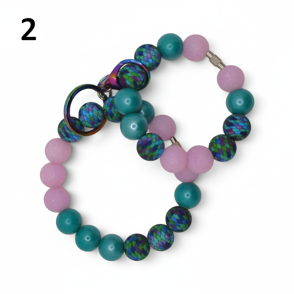 Flutterby Creations beadable wristlet with pink, teal, and patterned dragon scale beads and an iridescent ring.