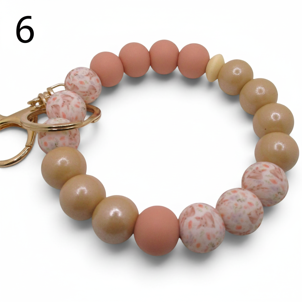 Flutterby Creations beadable wristlet with matte peach, tan, and speckled pink silicone beads and gold hardware.