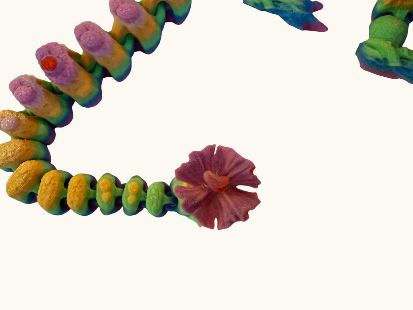 Flutterby Creations Elder Forest Dragon sculpture with rainbow gradient segments and a pink flower detail.