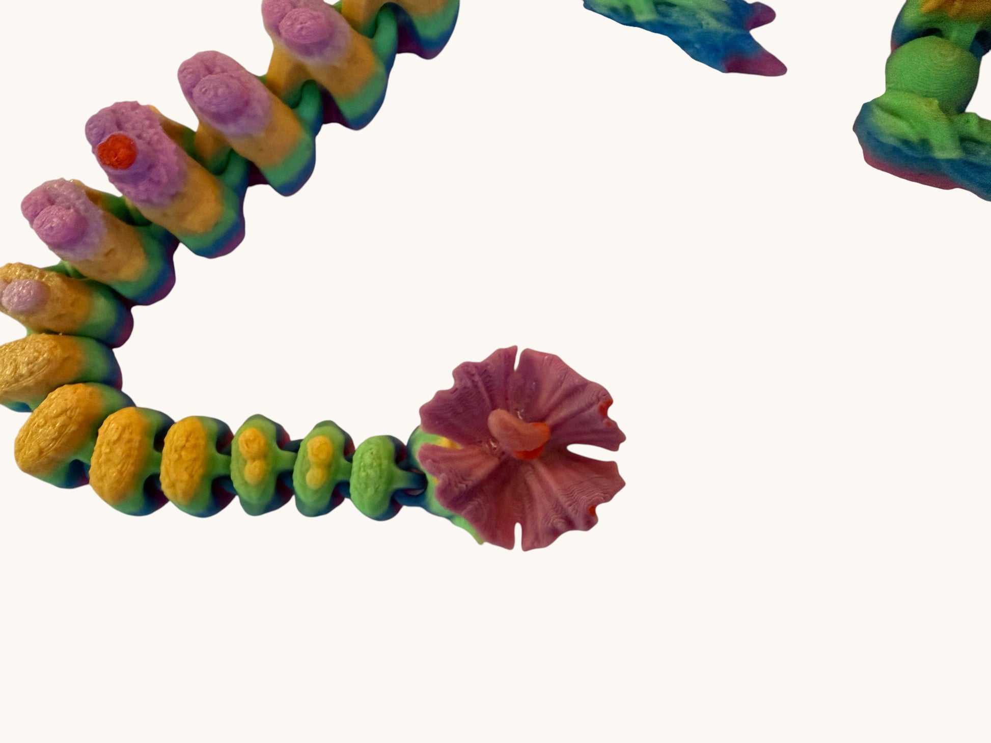Flutterby Creations Elder Forest Dragon sculpture with rainbow gradient segments and a pink flower detail.