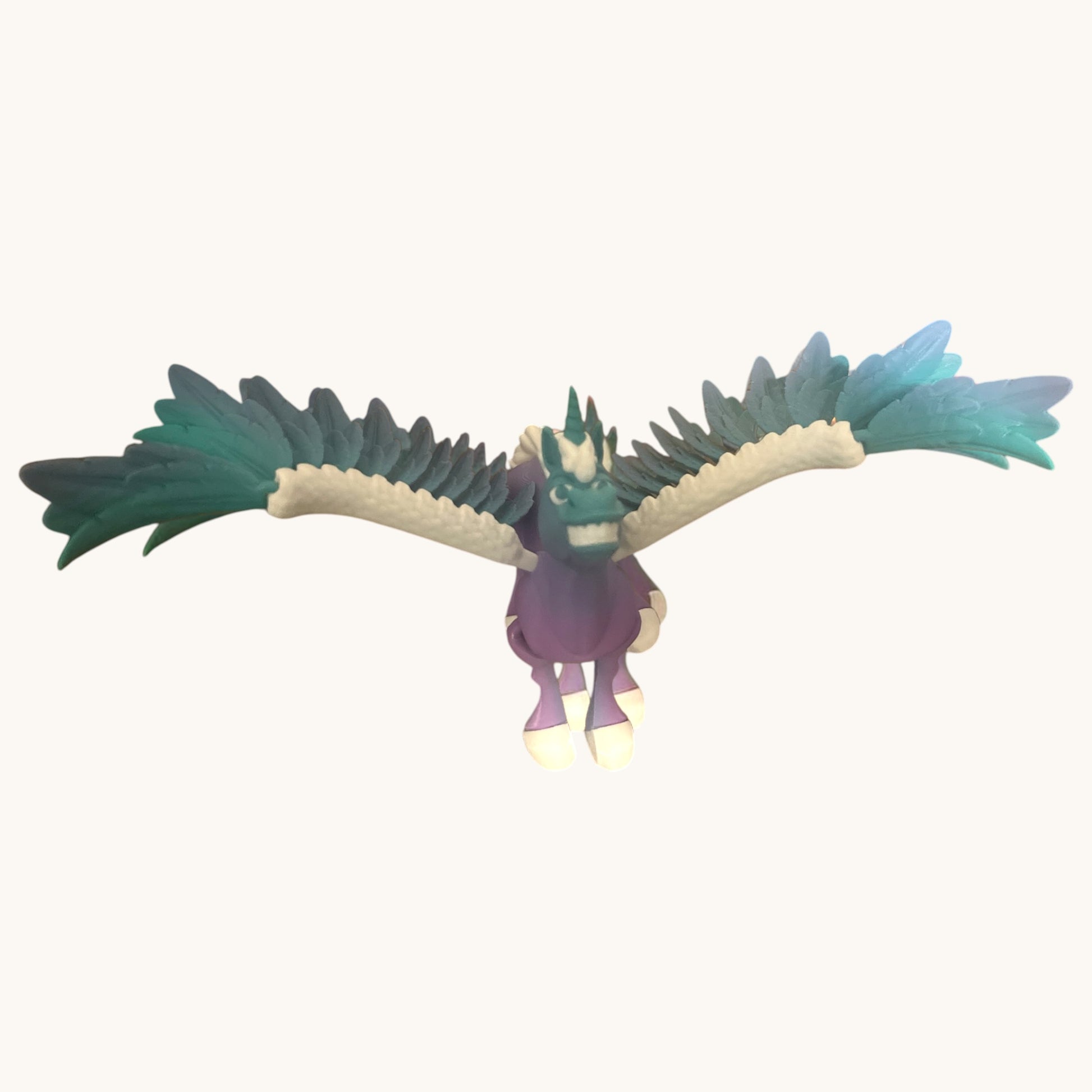 Flutterby Creations Flexicorn 3D printed purple unicorn toy with teal and white wings, grinning.