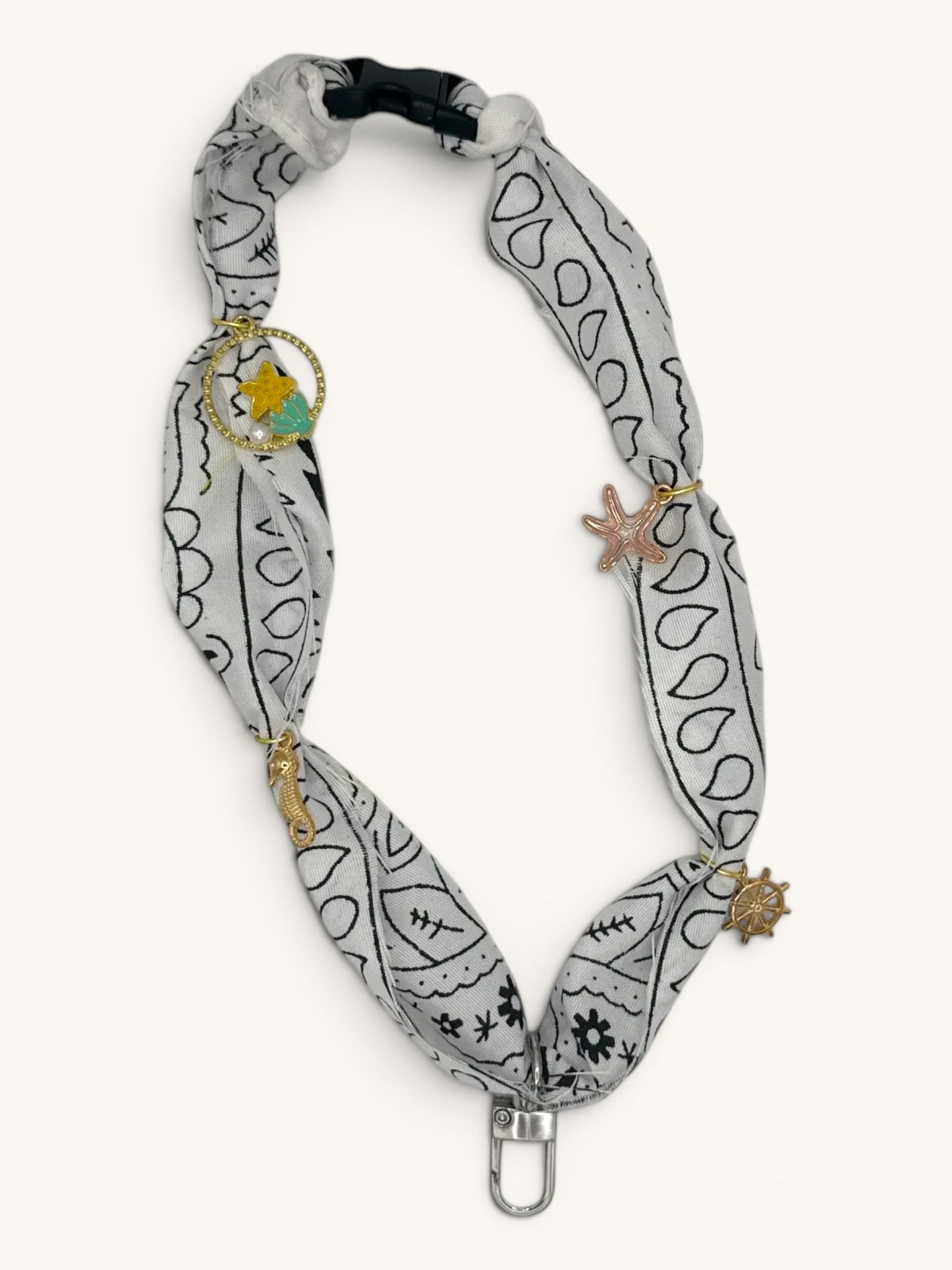 Flutterby Creations Freshie Hanger with a grey bandana print fabric, gold charms of a seahorse, starfish, ship wheel, and a star with teal accent.