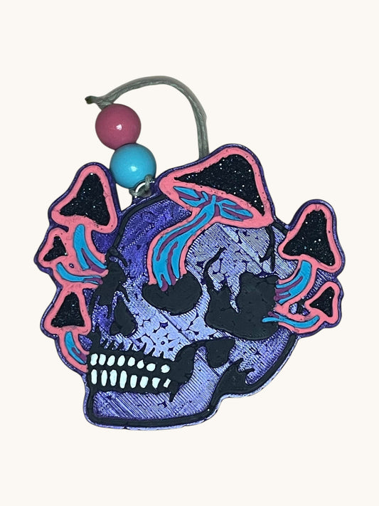 Flutterby Creations FungiSkull car freshie, a purple skull with pink and blue mushrooms, black glitter accents, and pink and blue beads.