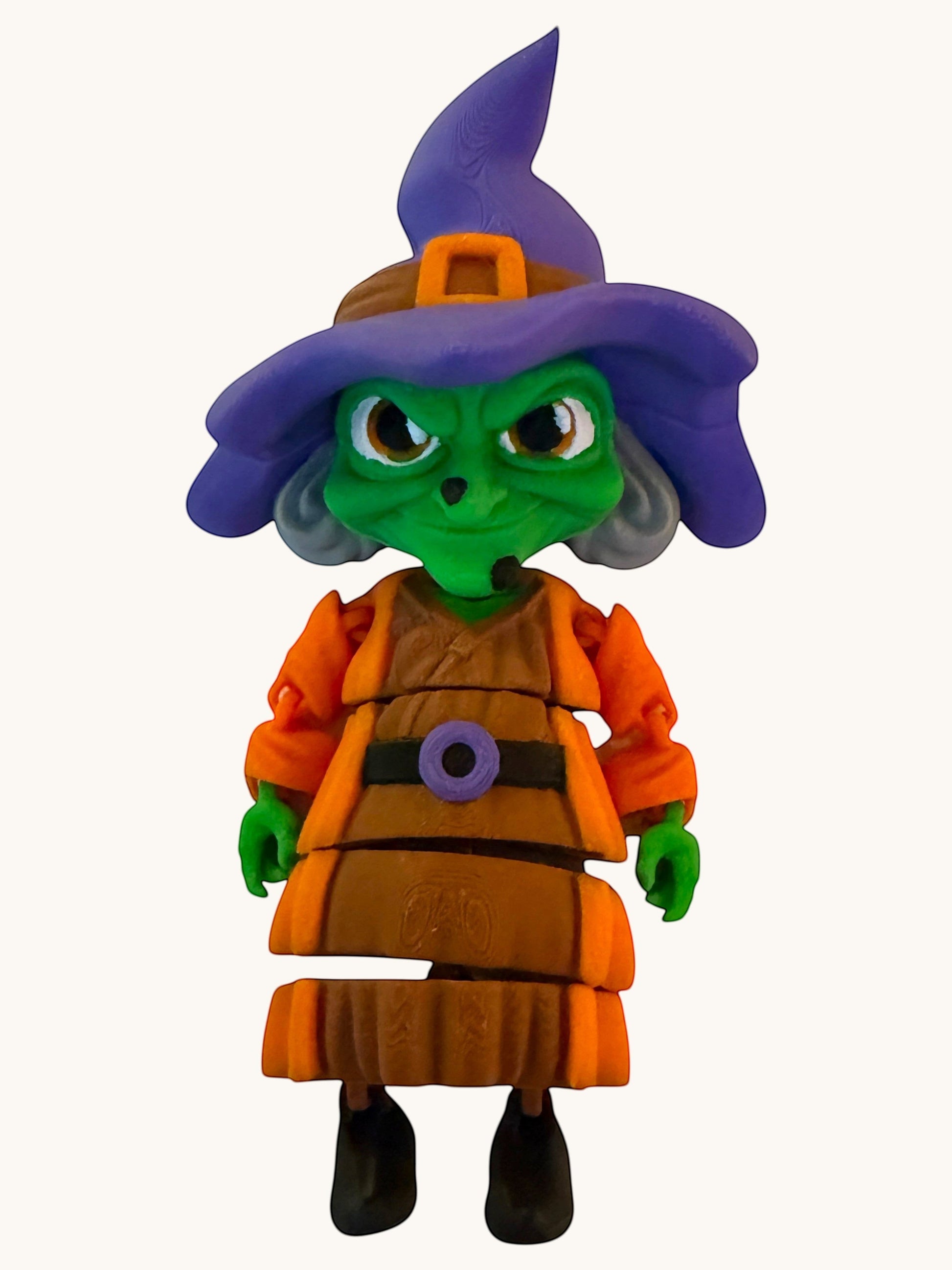 Flutterby Creations Halloween witch figurine with green face, purple hat, orange dress, and brown apron.