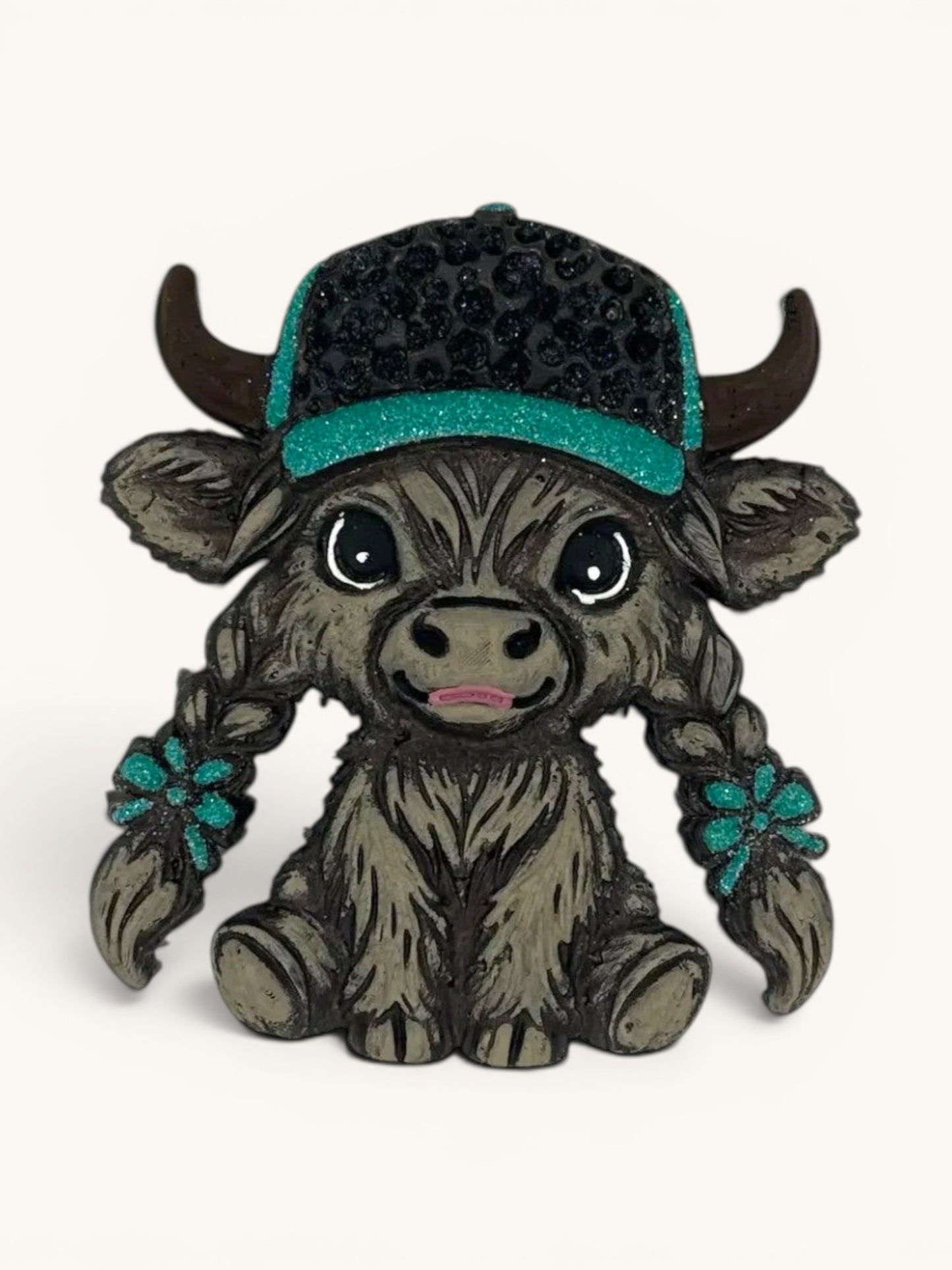 Flutterby Creations grey Highland cow figurine wearing a black baseball cap with teal brim and rhinestones, styled braids with teal flower accents.