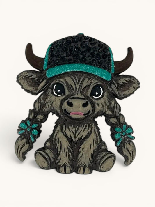 Flutterby Creations grey Highland cow figurine wearing a black baseball cap with teal brim and rhinestones, styled braids with teal flower accents.