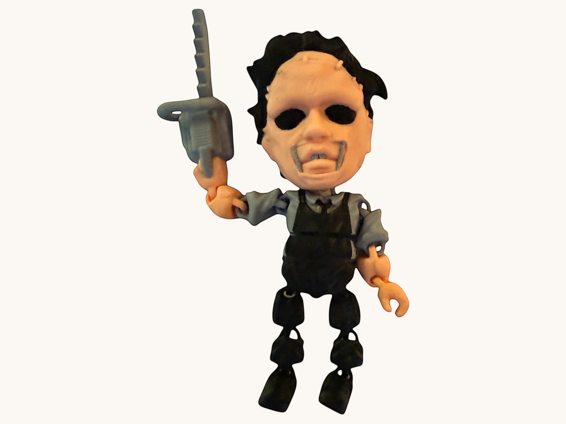 Flutterby Creations horror character figure with black hair, pale face, and holding a grey chainsaw accessory.