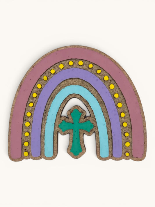 Flutterby Creations Rainbow Cross car freshie, handmade with aroma beads. Features pastel rainbow layers and a teal cross.