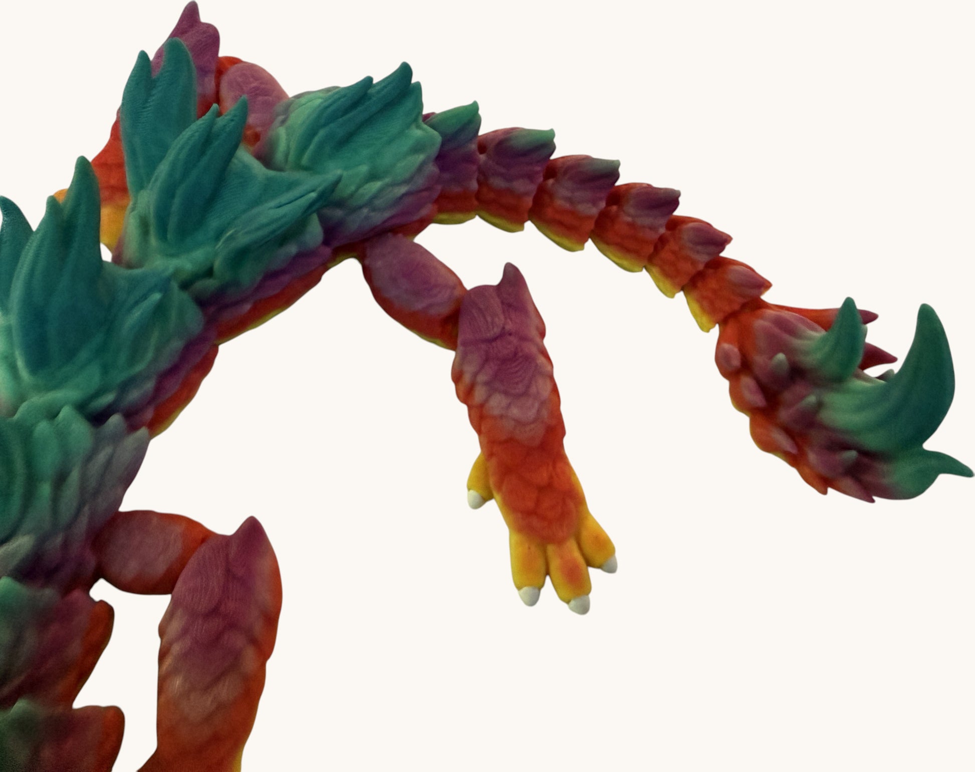 Flutterby Creations 3D printed flexible dragon toy with rainbow gradient colors: green, yellow, orange, pink, and purple.