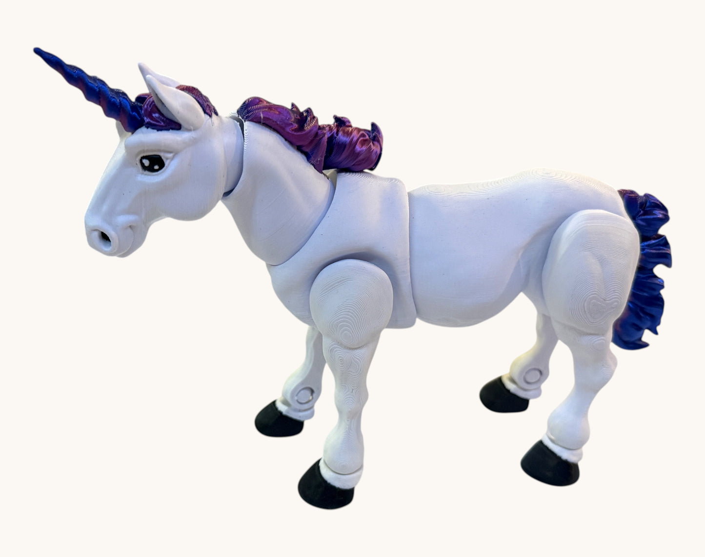 Flutterby Creations white 3D printed unicorn toy with purple mane and tail, blue horn, and black hooves.