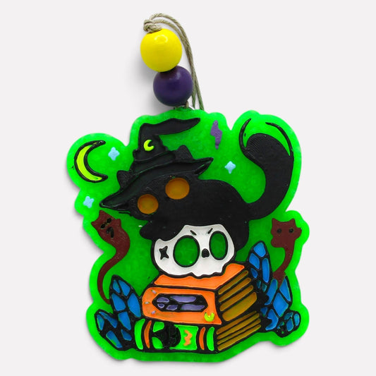 Flutterby Creations Witches Cat car freshie featuring a black cat, skull, and spellbook in vibrant green and orange.