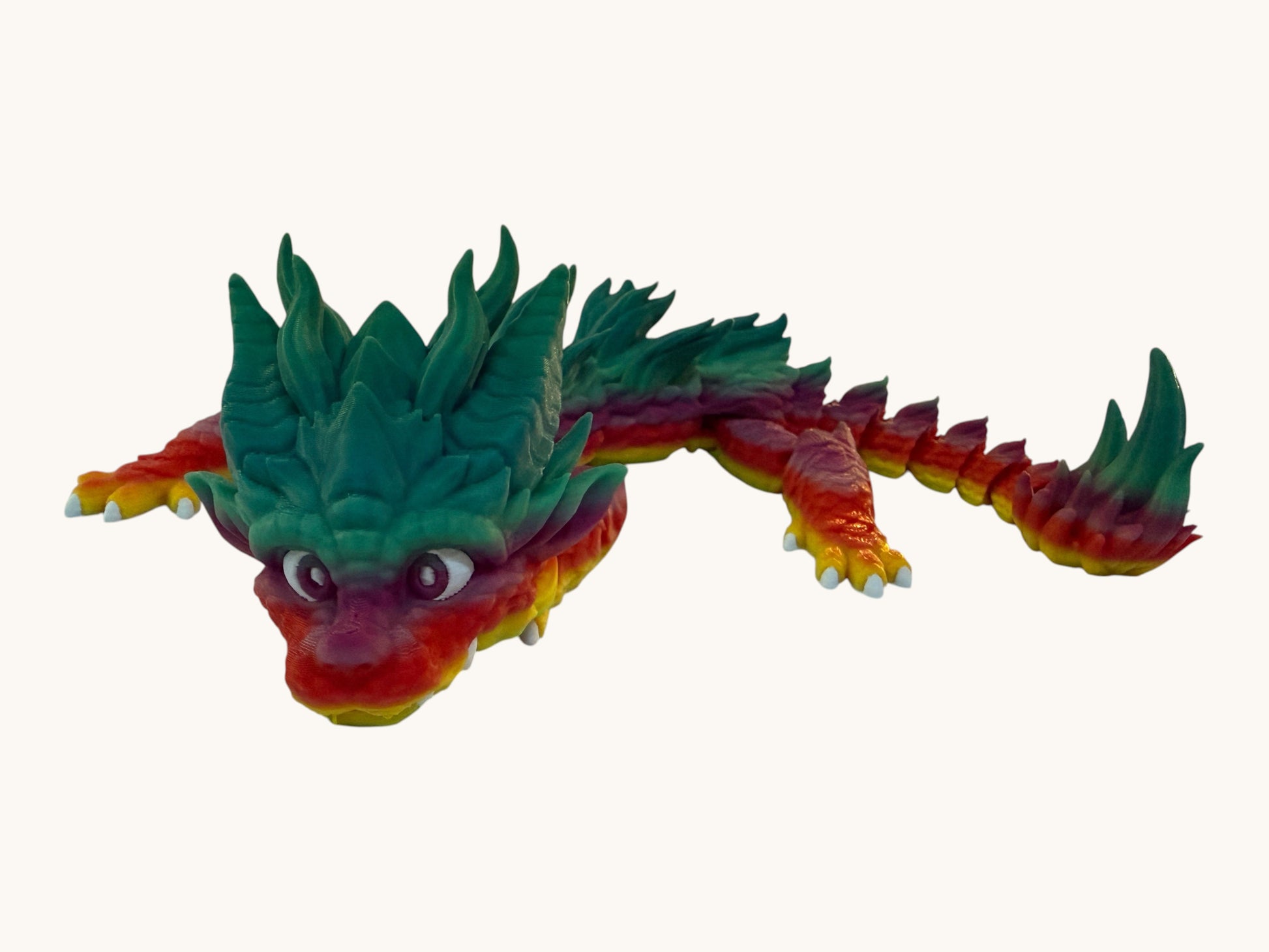 Flutterby Creations Young Dragon, a 3D printed flexible toy with a rainbow gradient from red and yellow to green. Features spiky crests and large, expressive eyes.