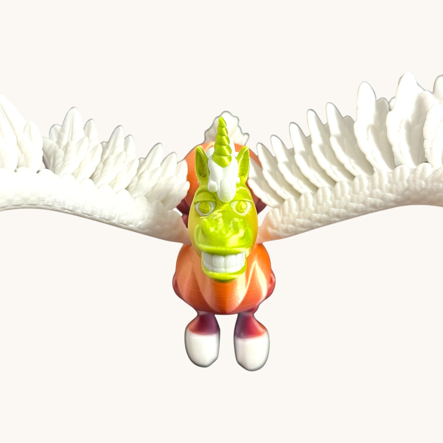 Flutterby Creations Flexicorn 3D printed toy unicorn with green head, orange body, white wings, and purple legs.