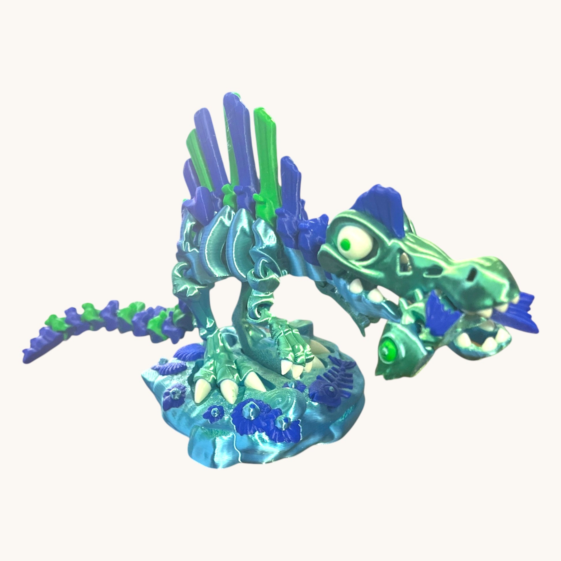 Flutterby Creations Skelisaurus 3D printed skeleton dinosaur toy in teal and blue with green accents, featuring a fish accessory and display stand.