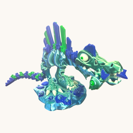 Flutterby Creations Skelisaurus 3D printed skeleton dinosaur toy in teal and blue with green accents, featuring a fish accessory and display stand.